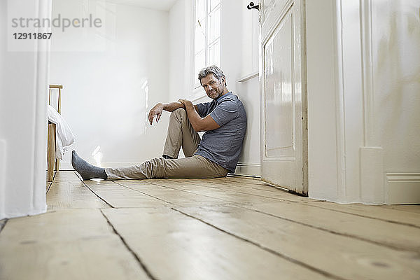 Mature man sitting on floor of his bedroom  daydreaming