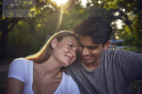Romantic young couple sitting in park  enjoying sunset