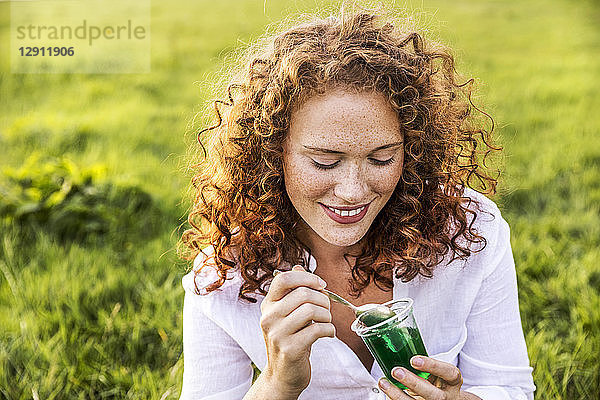 Portrait of smiling young woman eating jelly on meadow