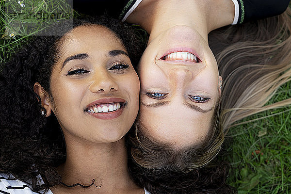 Two girlfriends relaxing in a park  lying on grass