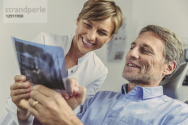 Dentist explaining x-ray image to smiling patient