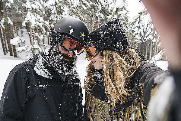 Selfie of couple in skiwear in winter forest