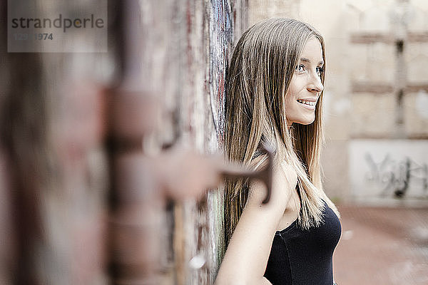 Smiling teenage girl leaning at a wall