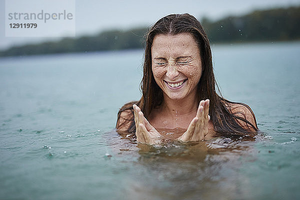 Portrait of freckled young woman bathing in lake on rainy day