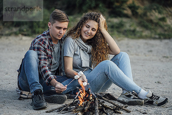 Romantic couple sitting at a campfire at he riverside
