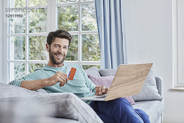 Portrait of smiling man at home shopping online
