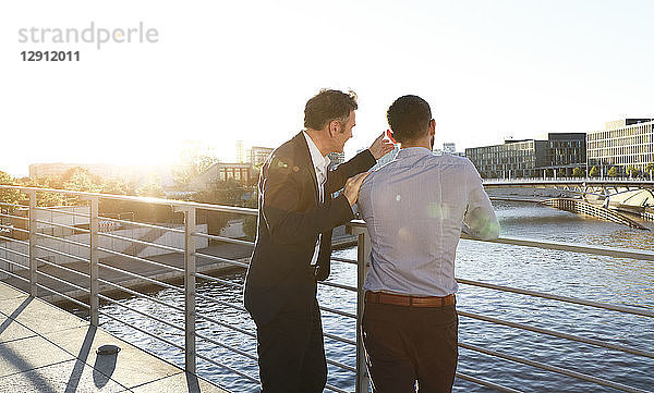 Two businessmen discussing on a bridge in the city