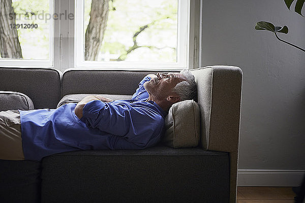 Mature man lying on couch at home