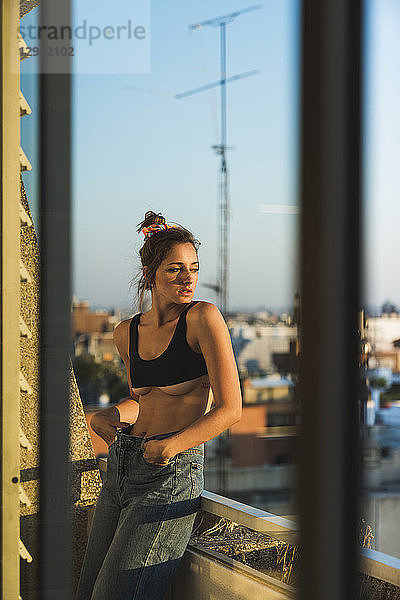 Young woman wearing bra standing on balcony