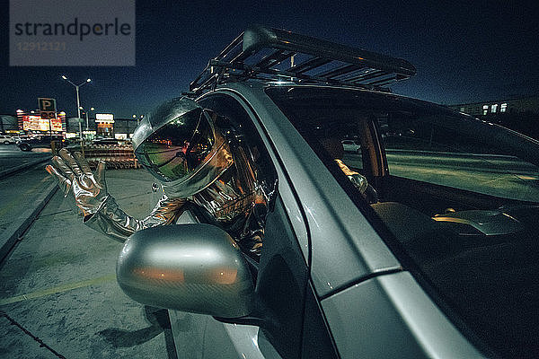 Spaceman waving out of car at night