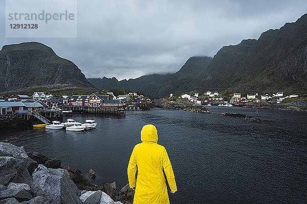 Norway  Lofoten  rear view of man standing in a fishing village at the coast