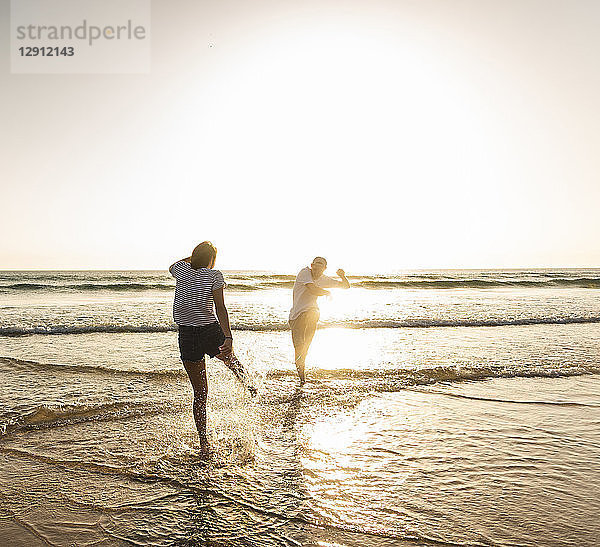 Young couple having fun at the beach  splashing water in the sea