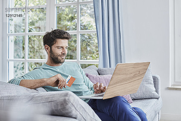 Smiling man at home shopping online