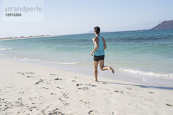 Spain  Canary Islands  Fuerteventura  rear view of young man running on the beach