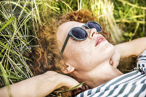 Young woman wearing sunglasses relaxing on a meadow