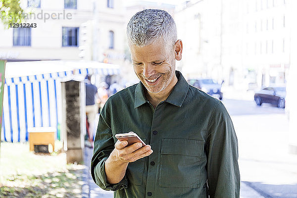 Smiling mature man using cell phone in the city