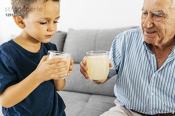 Grandfather and grandson drinking lemonade at home