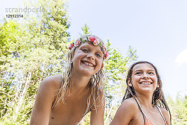 Portrait of happy girl wearing flower crown and friend outdoors in summer