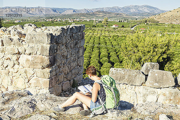Greece  Peloponnese  Argolis  Tiryns  archaeological site  female tourist reading guide book