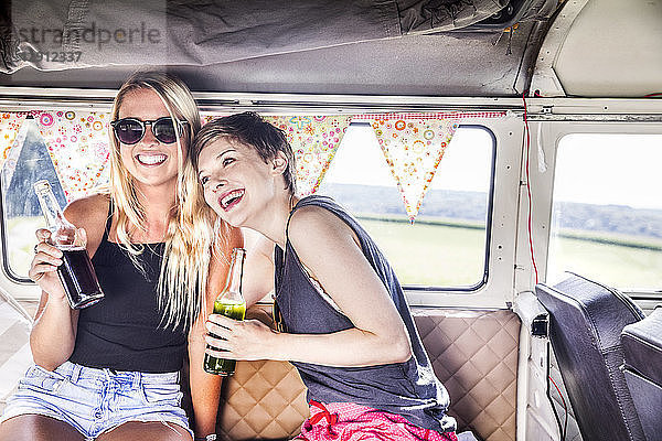Two happy women inside van with bottles