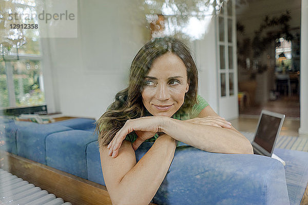 Smiling mature woman on couch at home looking sideways
