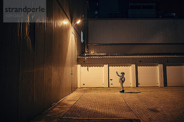 Spaceman standing under lamp at a yard at night