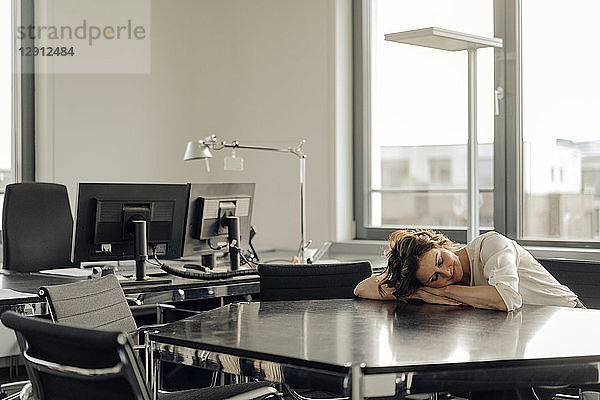 Tired businesswoman sleeping on her desk
