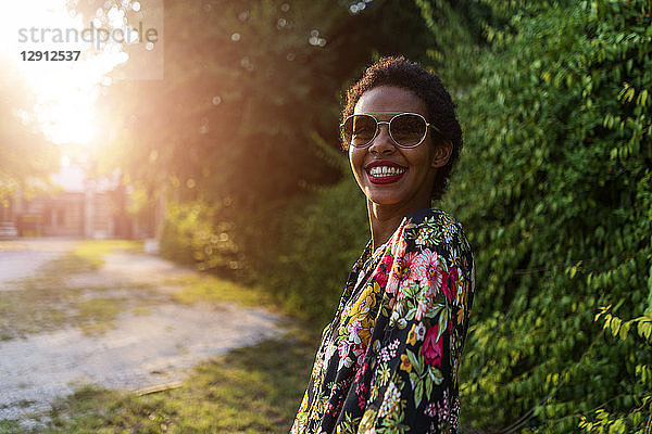 Portrait of happy young woman wearing sunglasses outdoors at sunset