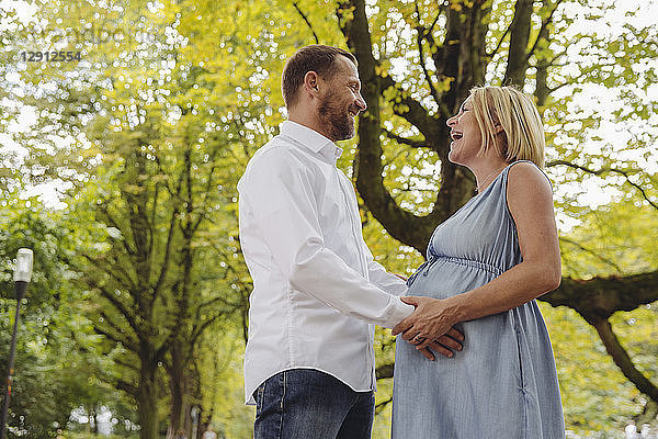 Happy mature pregnant couple talking in park