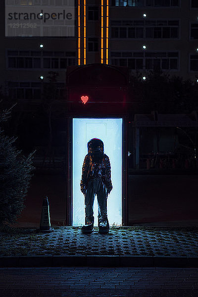 Spaceman standing at an illuminated box at night