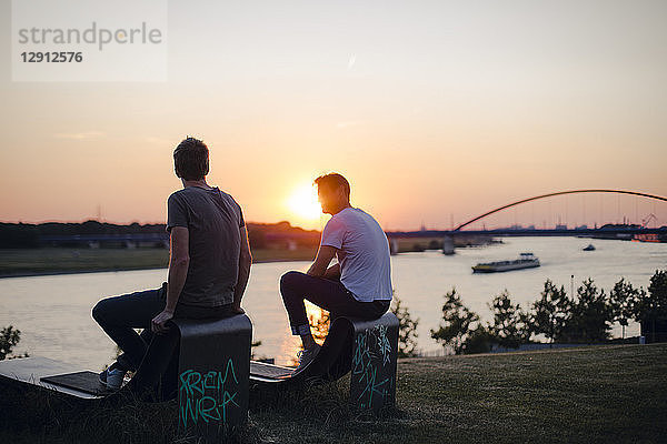 Two friends watching sunset at the river