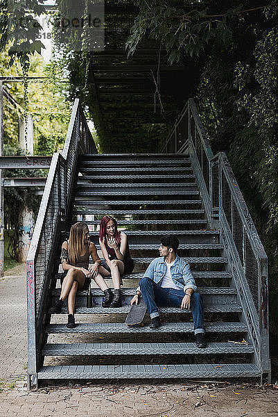 Friends with skateboard relaxing on stairs outdoors