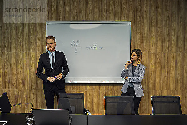 Businessman and businesswoman leading a presentation in boardroom