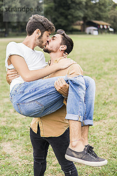 Kissing young gay couple in a park