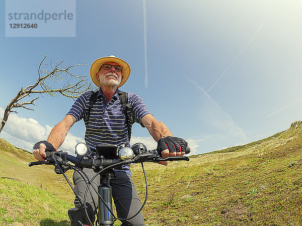 France  Bretagne  Sainte-Anne la Palud  Plage de Treguer  senior man riding mountain e-bike