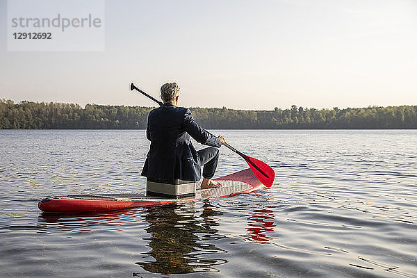 Back view of businessman paddling on lake