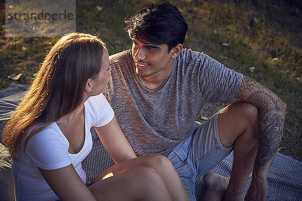 Romantic young couple sitting in park  enjoying sunset