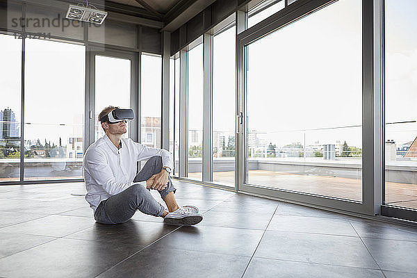 Businessman sitting in empty room wearing VR glasses