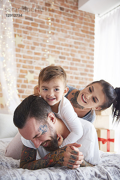 Happy family playing at Christmas time in bed