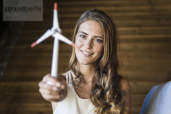 Portrait of smiling woman holding model wind turbine