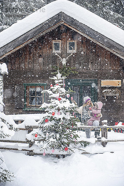 Austria  Altenmarkt-Zauchensee  mother with little son decorating Christmas tree at wooden house