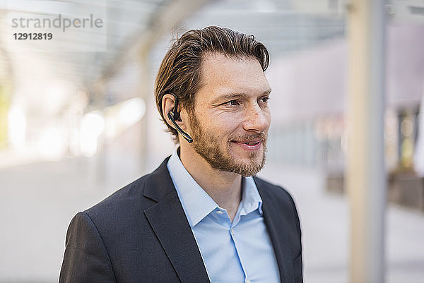 Portrait of smiling businessman wearing headset outdoors