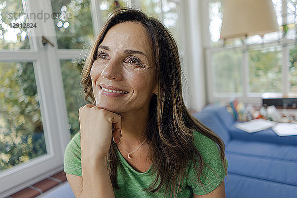 Smiling mature woman on couch at home looking away