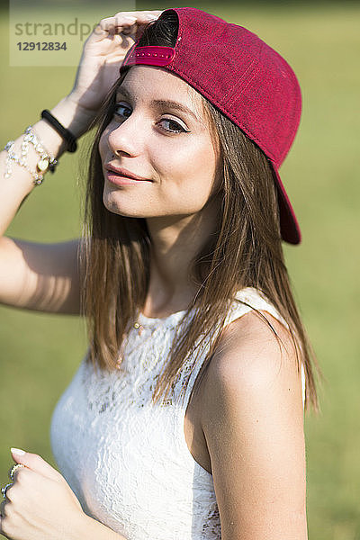 Portrait of smiling young woman wearing baseball cap outdoors