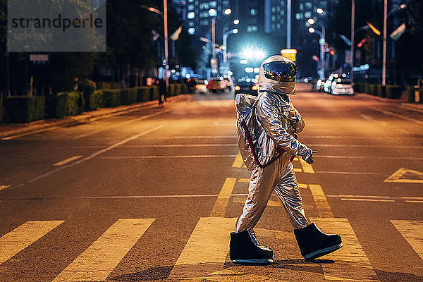 Spaceman walking on a street in the city at night