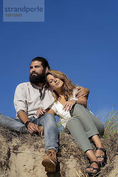 Young couple sitting on a dune in summer  relaxing