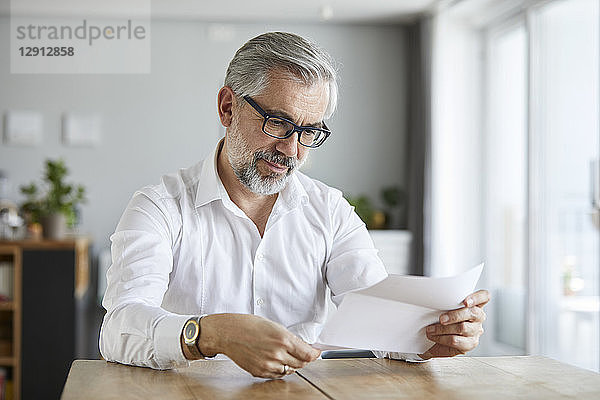 Portrait of mature man reading letter at home