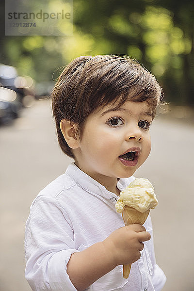 Portrait of toddler with vanilla ice cream cone in park