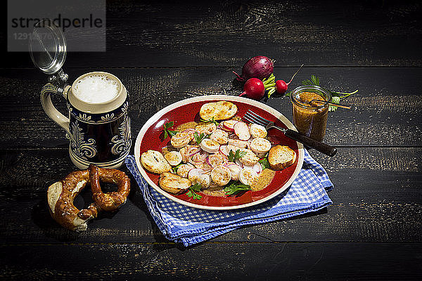 Bavarian veal sausage salad with roasted pretzel rolls  sweet mustard  pretzels  red radish and beer mug
