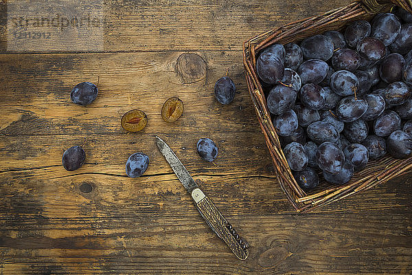Wicker basket of organic plums  wooden table